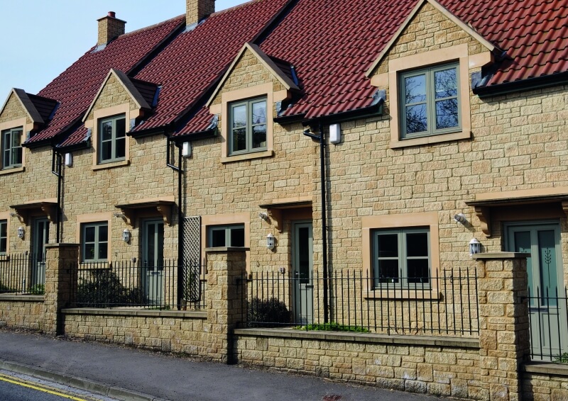Row of traditional stone-built houses featuring Rio flush sash windows with a clean, modern finish that blends seamlessly with the heritage-style design.